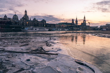 Dresden, Germany old town skyline on the Elbe River at sunset in the winter with ice in the foreground.