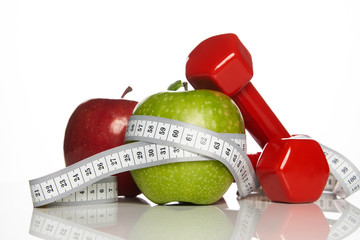 Green and Red apples with measuring tape and red weight dumbbells for diet concept on white background, close-up. Healthy lifestyle, fitness and weight loss concept