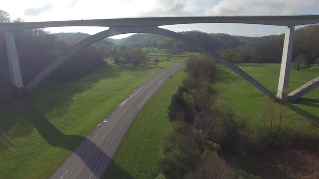 Following Highway Under Bridge Through Lush Green Hills