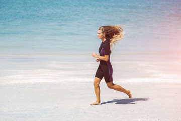Beautiful woman in wetsuit on the idyllic beach