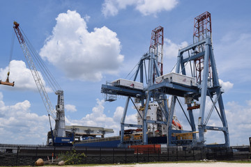 Fototapeta na wymiar Cargo shipping port structures and cranes, sunny day.