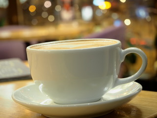 Cappuccino cup against background of lights