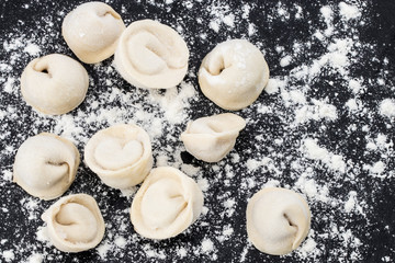 Traditional russian pelmeni, ravioli, dumplings with meat on black  stone background . Copyspace