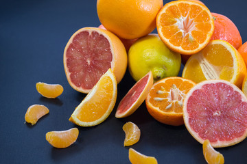 Colored Citrus fruits on a dark blue background. Slices of citrus and peel. Citrus reticulata. Citrus paradisi. Citrus limon. Citrus sinensis.