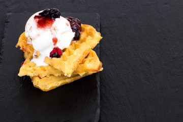 Plate of belgian waffles with ice cream and jam on dark  background