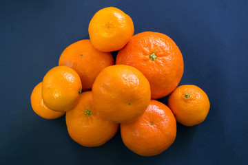 Bright mandarins are harmoniously lying on a dark blue background.