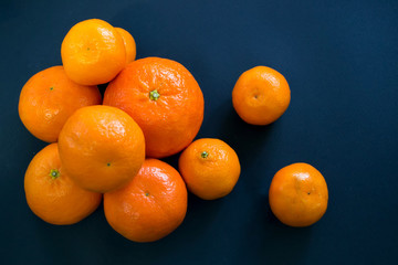 Bright mandarins are harmoniously lying on a dark blue background.