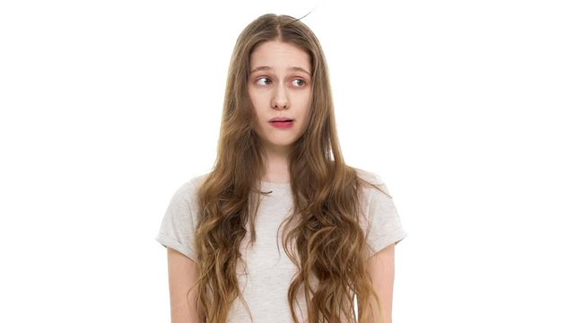 Portrait of young cute teenage woman 17 years old blowing lock of her brown long hair in slow motion, isolated over white background closeup. Concept of emotions