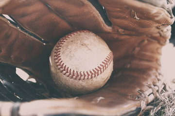 Athletic American sport shown with dirty ball in leather baseball glove.