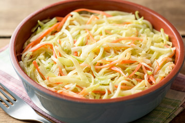 Fresh coleslow salad in bowl on rustic wooden table