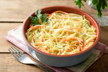 Fresh coleslow salad in bowl on rustic wooden table
