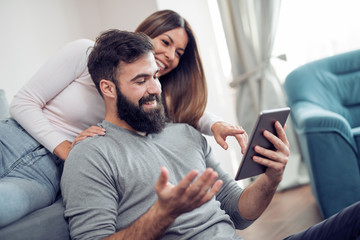 Young couple using a tablet in living room