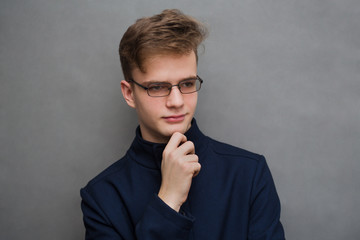 Fototapeta premium portrait of an attractive stylish serious young man, teenager in a coat and glasses