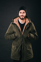 Naklejka na ściany i meble Young bearded man in denim jacket with shearling liner shows his chest wearing black unlabeled henley shirt longsleeve, isolated on grey wall in studio looks into camera