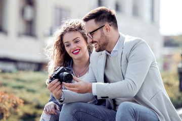 Tourist couple taking photos with camera on street.