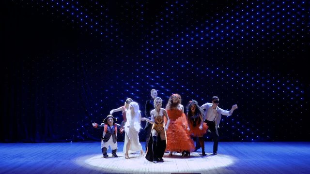 People dressed in scenic costumes are dancing on stage in theatre