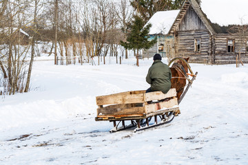 a villager in a village goes in a makeshift sleigh and runs a horse, winter day