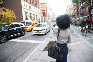 Woman hailing a taxi cab on a busy city street