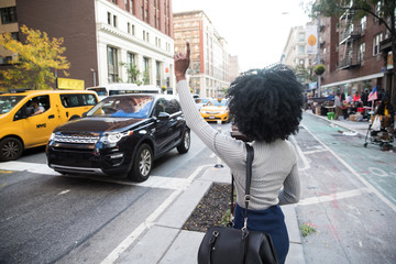 Woman hailing a taxi cab on a busy city street