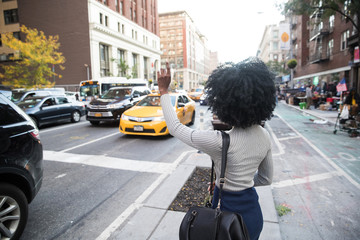Woman hailing a taxi cab on a busy city street