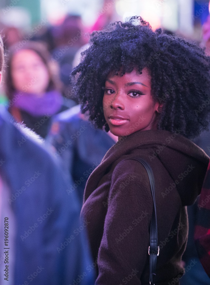 Wall mural Pretty African American Girl looking back over her shoulder in crowded city