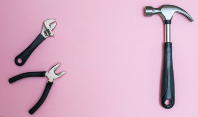 Working tools: hammer and pliers on pink, creative background for custom diy message.