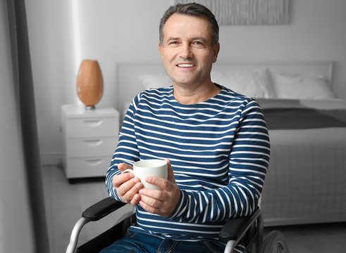 Mature man in wheelchair drinking coffee indoors