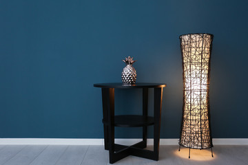 Floor lamp with table near color wall