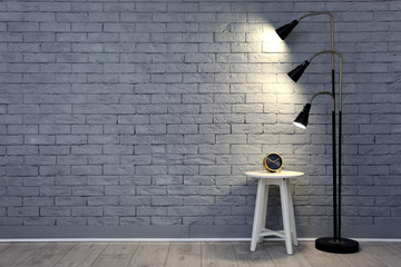 Floor lamp and small table near brick wall