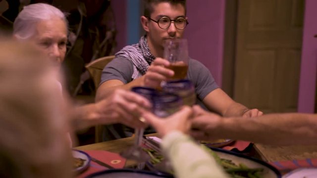 Steadicam moving around the table as a family clinks their glasses at the start of their dinner.