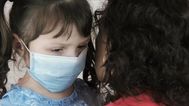 Sad child in a medical mask. Mom hugs a sick child.