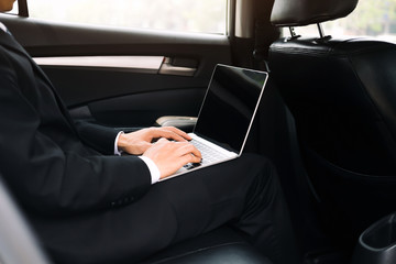 Businessman using computer working car inside