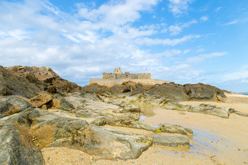 Fototapeta na wymiar Low view of Saint Malo beach, Fort National and rocks during low Tide. Brittany, Europe
