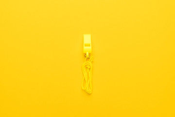 plastic referee whistle on the yellow background