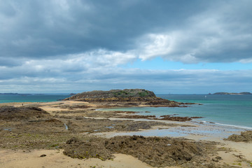 Fototapeta na wymiar French beach with small island, rocks, stones and cloudy cold windy day