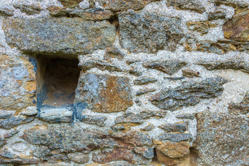 Medieval stone wall with a small window carved on