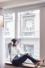 Fashion photo of sensual brunette woman sitting by the window and looking outside,copy space ,concept fashion