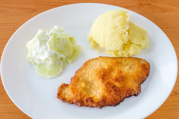 Kotlet schabowy with mizeria and mashed potatoes.