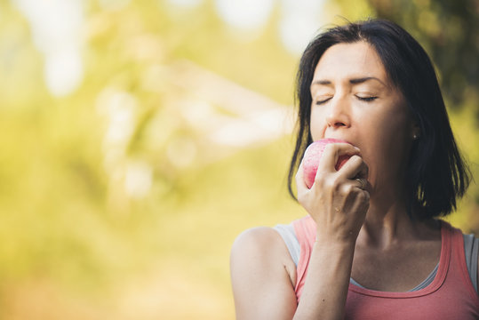 Older Woman Is Eating Apple After Exercising To Take Care Of Their Health.Eat Healthy Eating Concept.