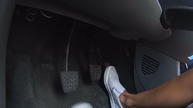 Woman legs pushing pedals, starting car engine and going to work, inside view