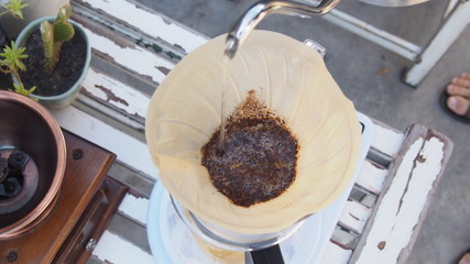 hand drip coffee, barista pouring hot water over roasted grinded coffee powder making drip brew...