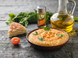 A bowl of freshly made hummus and pita on a rustic table.