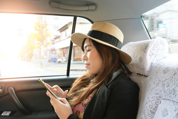Asian woman is using smart phone while traveling in Japan inside Taxi Car.