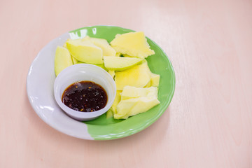 Sliced ​​mango and sweet fish sauce in dish on wooden table