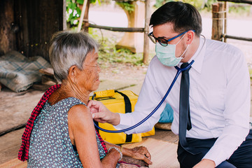 Male Doctor listening heart beat and breathing of Elderly Woman with Stethoscope with First Aid...
