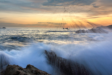 Splash of wave on seascape at sunset in Phuket, Thailand.