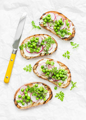 Spring sandwiches - grilled bread, cream cheese, green peas, radishes and micro greens. Healthy eating, slimming, diet lifestyle concept. On a light background, top view. Flat lay