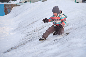 Fototapeta na wymiar Funny little kid boy in colorful clothes playing outdoors in winter on cold snowy days. Happy child having fun and playing with snow