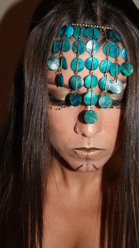 Portrait of a beautiful woman model with a tribal fantasy fashion make up style in brown and gold