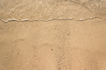 Soft waves with foam of ocean on the sandy beach background